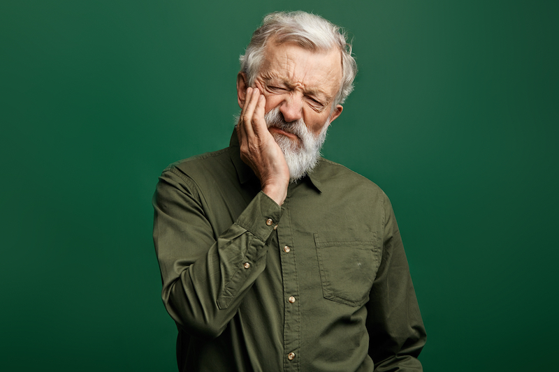 Senior man holding cheek suffering from toothache