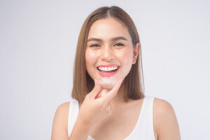 smiling woman holding invisalign braces