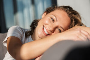 Smiling pretty blonde young woman wearing casual clothes relaxing on a couch at home