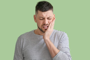 Man suffering from tooth ache on color background