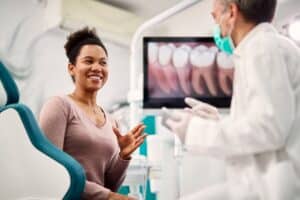 Happy,African,American,Woman,Talking,To,Her,Orthodontist,At,Dentist's