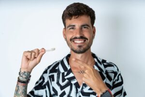 Young,Caucasian,Man,Wearing,Printed,Shirt,Holding,An,Invisible,Aligner