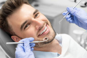 Man smiling in dentist chair after having dental bridge replace missing teeth in Las Vegas, NV