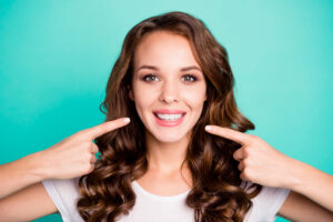 Beautiful happy woman pointing to her perfect smile after smile makeover treatments in Las Vegas, NV
