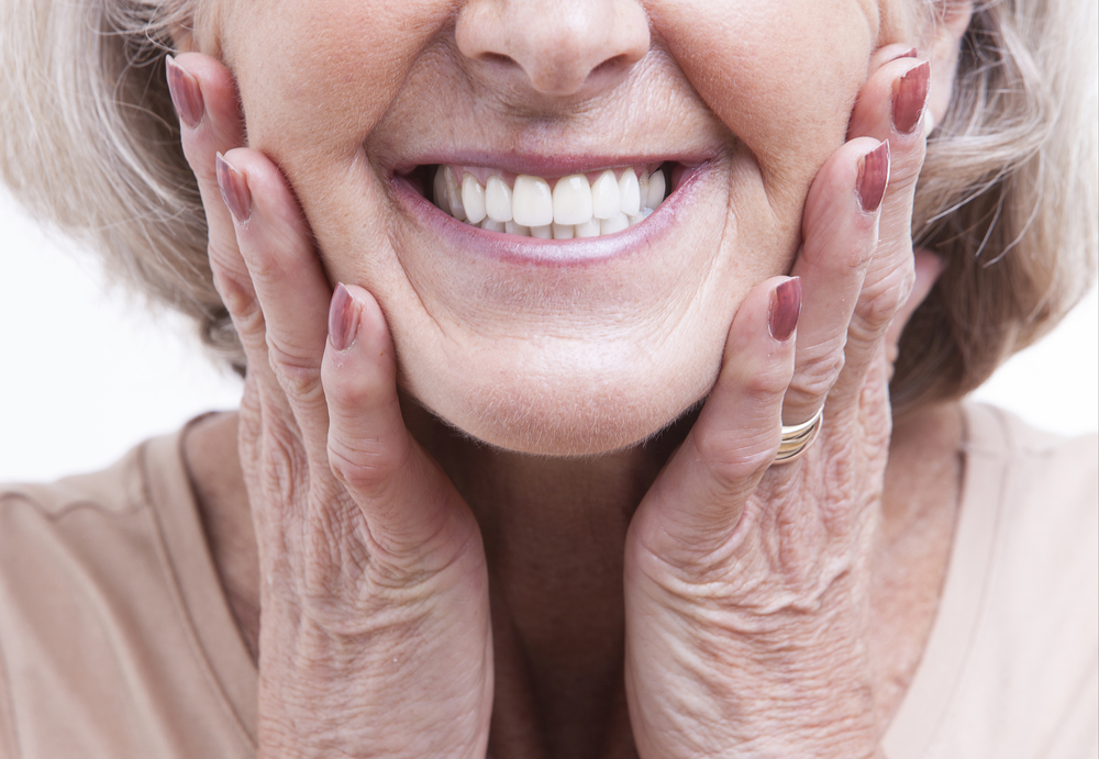 A close-up shot of a woman smiling and showing her LOCATOR FIXED dentures